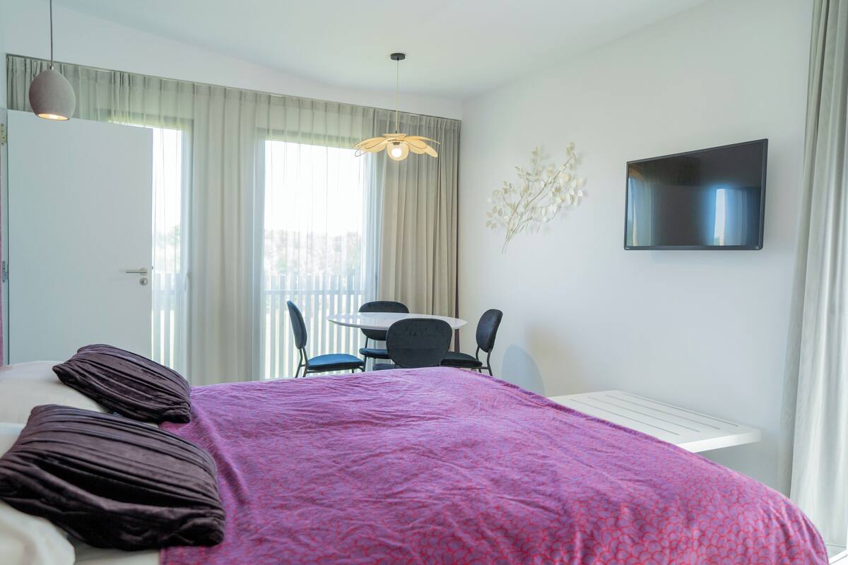 Ein Hotelzimmer mit Bett, Schreibtisch und Fernseher.