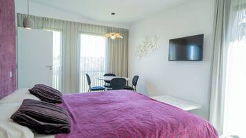 A hotel room with a bed, a desk, and a TV.