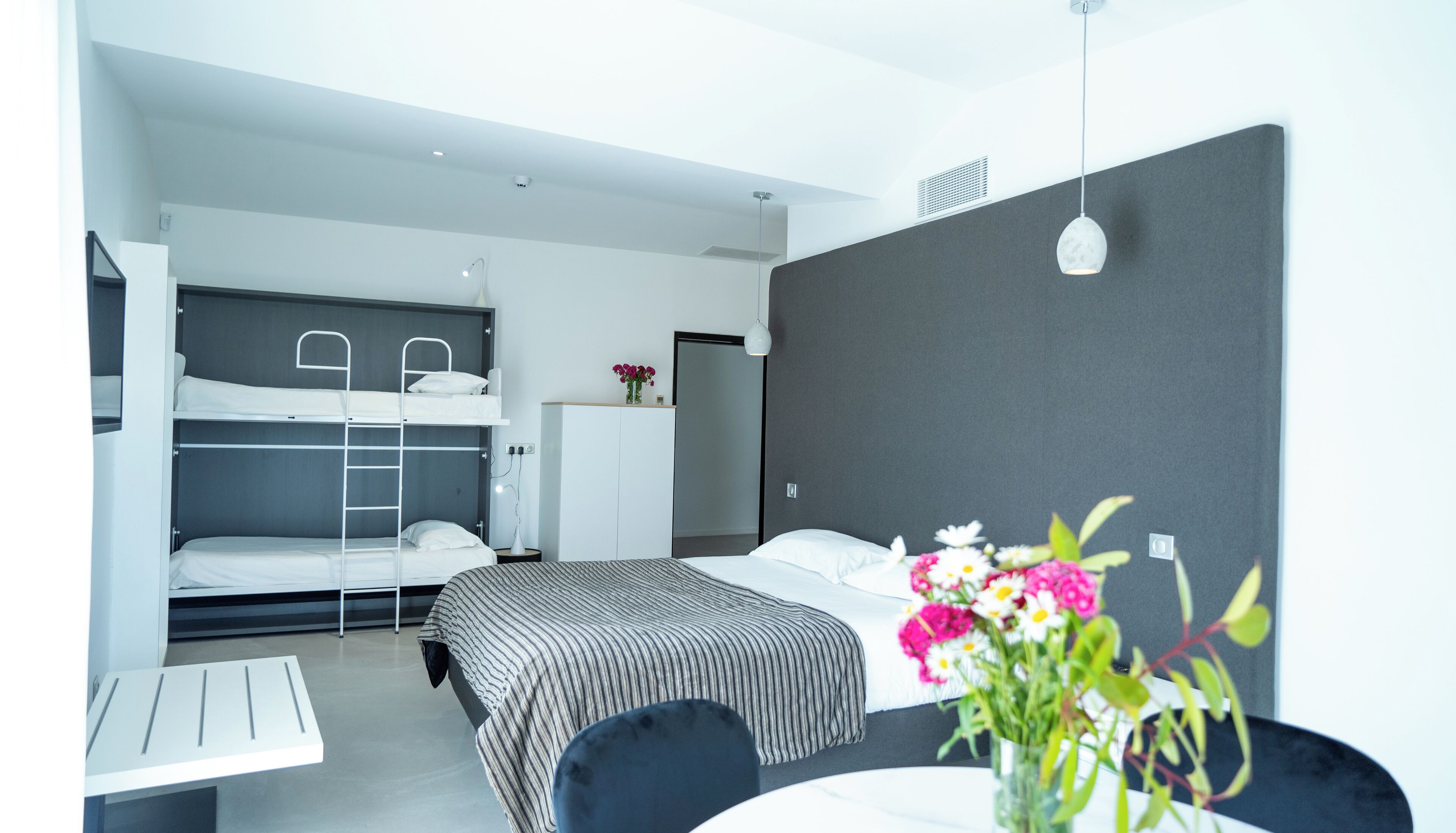 A modern hotel room with bunk beds, a desk, and a bedside table.
