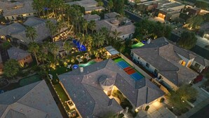 Vista aérea de un barrio residencial con casas, una piscina y una cancha de tenis.