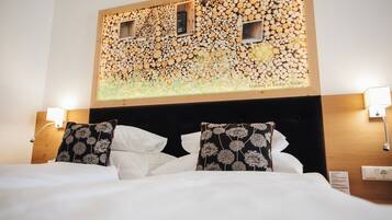 Ein Hotelzimmer mit einem Bett, weißer Bettwäsche, zwei Zierkissen, einem Kopfteil mit einer Wand aus Holzbalken und zwei Wandleuchten.