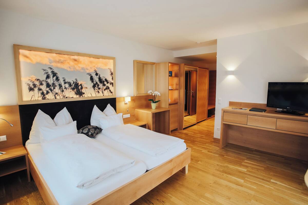 Ein Hotelzimmer mit einem großen Bett, einem Schreibtisch, einem Fernseher und einem Gemälde an der Wand.