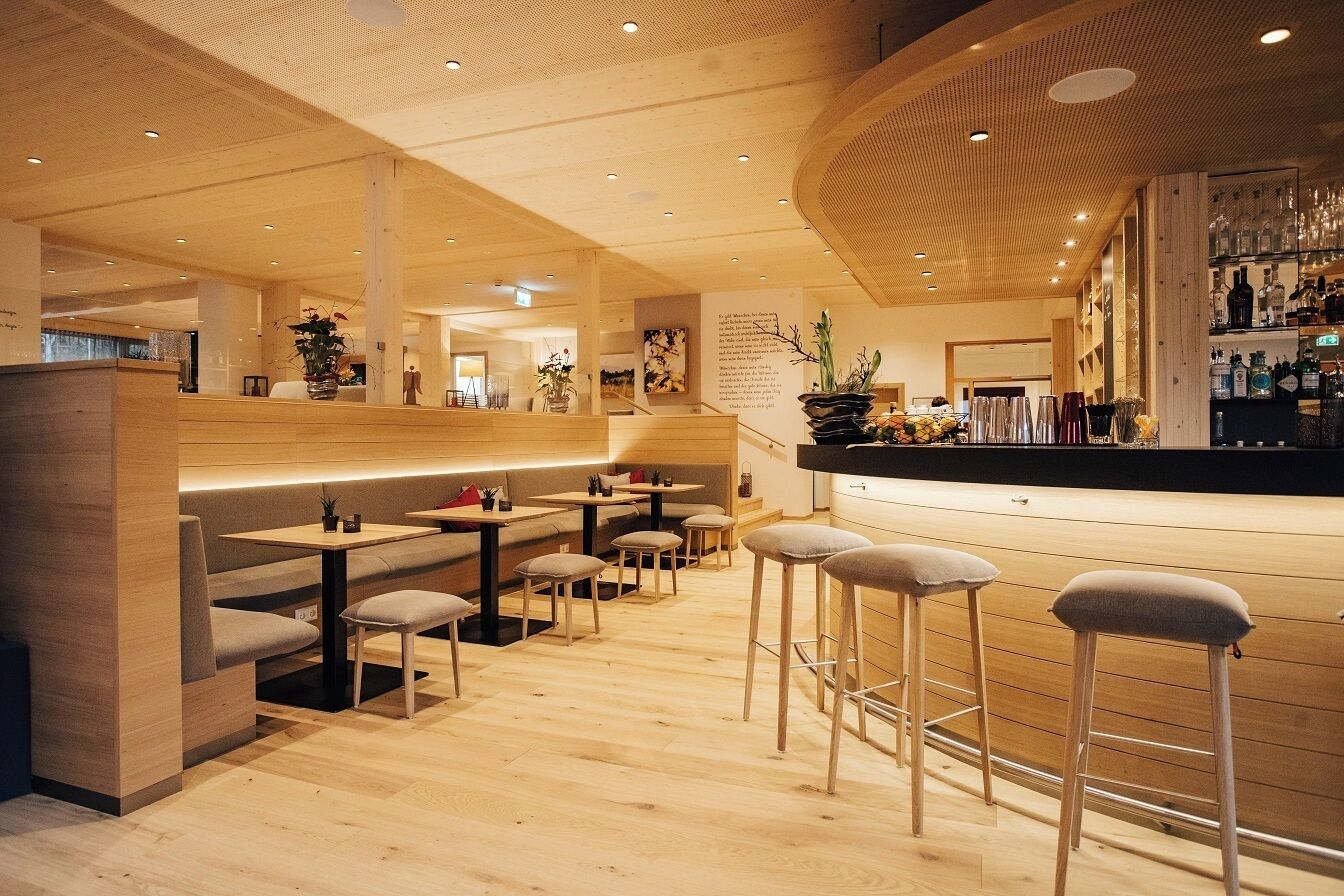 A modern interior with wooden flooring, bar area, and seating arrangements.