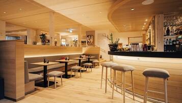 A modern interior with wooden flooring, bar area, and seating arrangements.
