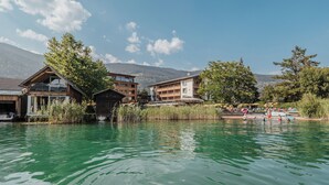 A lakeside hotel with wooden buildings, a dock, and a clear view of mountains in the background.