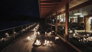 A deck with candles, seating, and a view of the night sky.