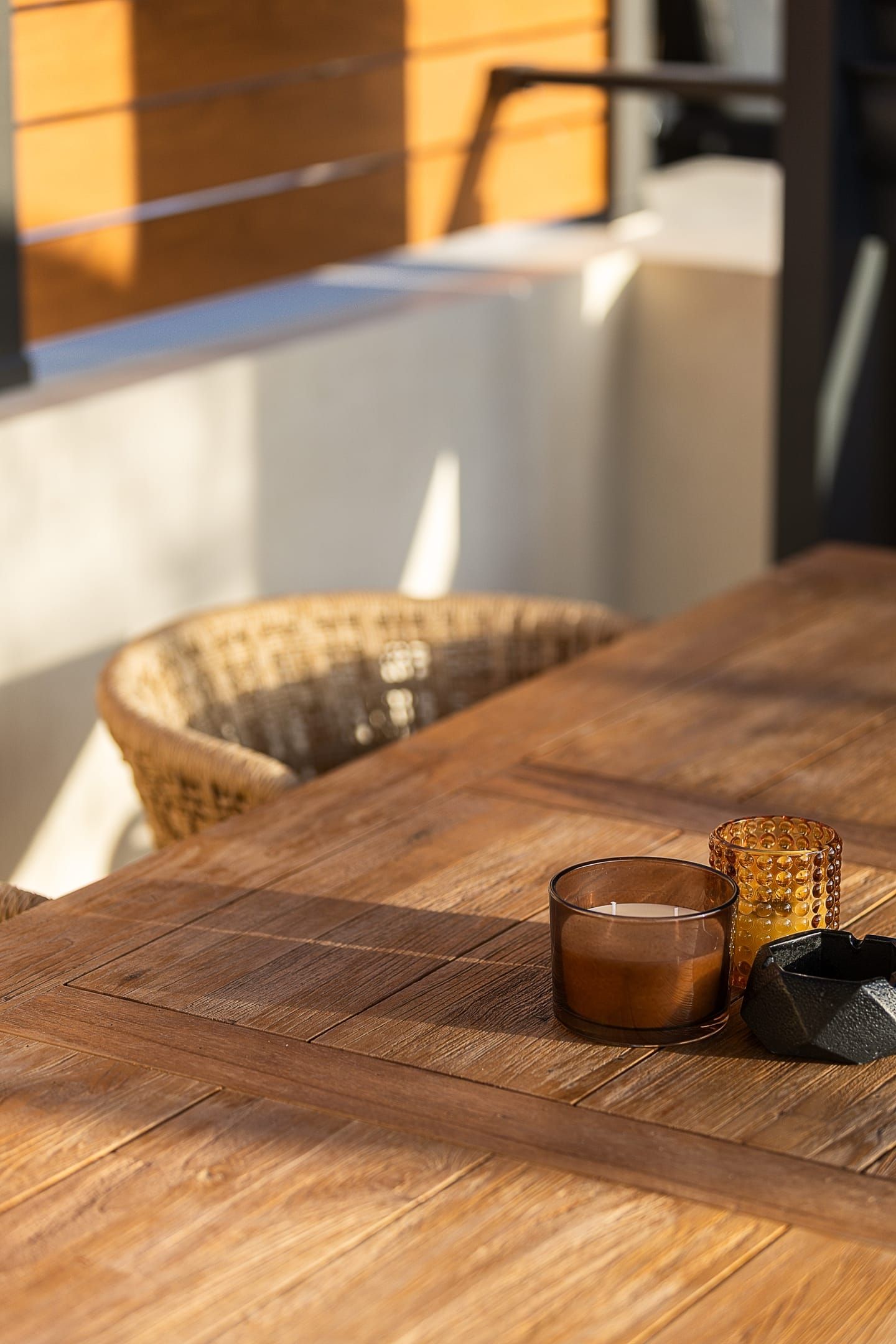 Een houten tafel met een kaars, een glas en een rieten mand.
