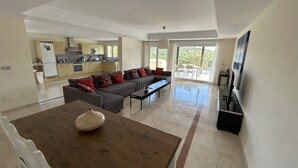 A spacious living area with a sofa set, a dining table, and a kitchen in the background. - Luxury Apartment San Roque Club. Spacious, large balcony overlooking mountains (San Roque)