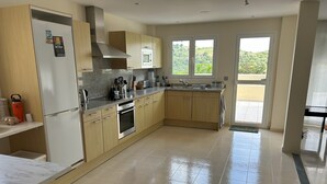 A modern kitchen with a built-in oven, microwave, and stainless steel range hood. There are wooden cabinets and a granite countertop. - Luxury Apartment San Roque Club. Spacious, large balcony overlooking mountains (San Roque)
