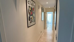 A hallway with a marble floor, a framed artwork on the wall, and a door at the end. - Luxury Apartment San Roque Club. Spacious, large balcony overlooking mountains (San Roque)