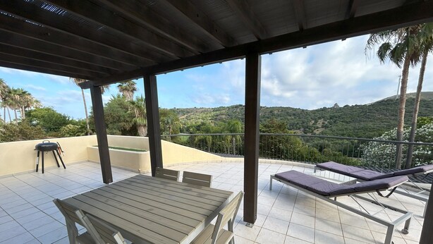 An outdoor patio with a table and chairs, a grill, and lounge chairs. - Luxury Apartment San Roque Club. Spacious, large balcony overlooking mountains (San Roque)