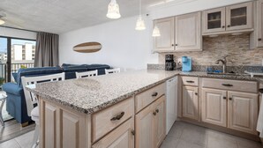 A modern kitchen with granite countertops, wooden cabinets, and pendant lighting. - New For 2025! Charming 1 bedroom condo oceanblock in North OC (Ocean City)