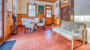 A cozy room with a wooden ceiling, a dining table with chairs, a sofa, and a staircase. - Cliffwood Cottage by Evergreen Home (Lenox)