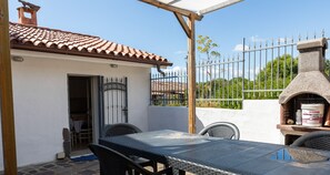 Enjoy dining or socializing in this outdoor patio area with a table and four chairs, featuring a stone oven for cooking or grilling.