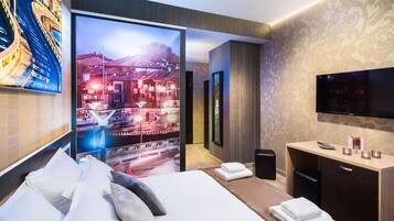 Une chambre d’hôtel moderne dotée d’un grand lit, d’une télévision, d’un bureau et offrant une vue sur le paysage urbain.