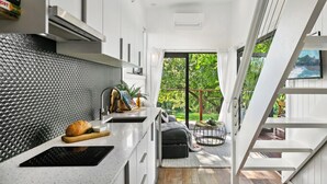 Una cocina moderna con encimera negra, hogaza de pan y una planta.