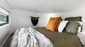 Un dormitorio con cama, ventana y un adorno en la pared.