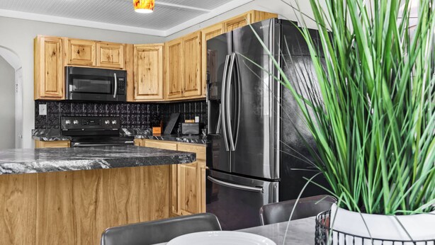 Une cuisine moderne avec des meubles en bois, un réfrigérateur en acier inoxydable, un four à micro-ondes et un plan de travail en marbre.