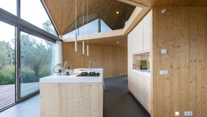 A modern kitchen with wooden cabinetry, a central island with a sink, and pendant lighting. - 3 bedroom lovely home in Warten (Warten)