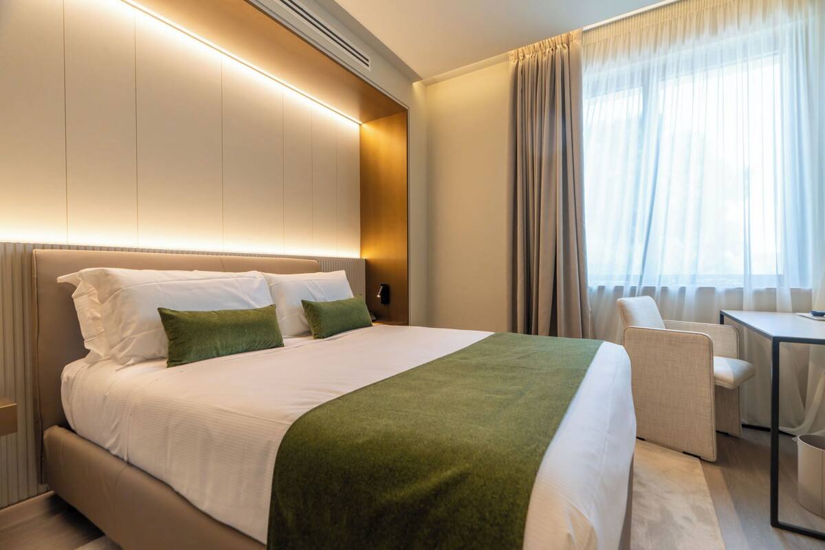 A hotel room with a large bed, a desk, and a chair.