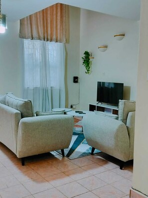A living room with a sofa set, a television, and a small table. - Lux Suites Anahita Apartments Parklands (Nairobi)
