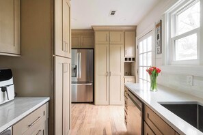 Una cocina con armarios de madera clara, un refrigerador de acero inoxidable y una ventana con vistas al exterior.