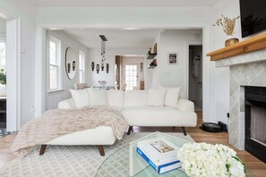 Una sala de estar moderna con un sofá blanco, una mesa de centro de vidrio y una chimenea.