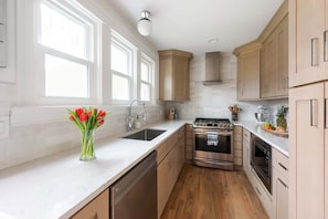 A kitchen with white cabinets, stainless steel appliances, and a window with a view.
