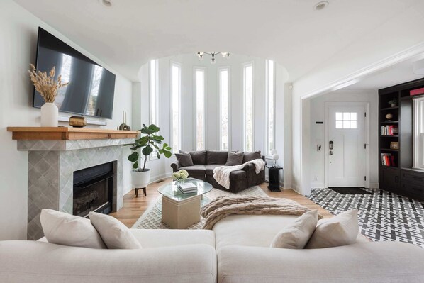 A modern living room with a fireplace, a large TV, and a cozy seating area.