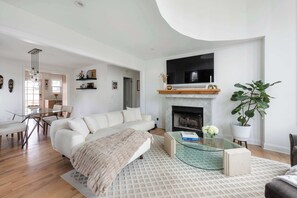 Una sala de estar moderna con sofá, mesa de centro, chimenea y televisor montado en la pared.