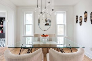 Un coin repas avec une table en verre, quatre chaises et des luminaires sphériques suspendus.