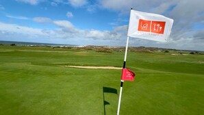 Ein Golfplatz mit einer Fahne, die ein Loch markiert.