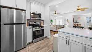 Una cocina moderna con electrodomésticos de acero inoxidable, armarios blancos y una isla central.