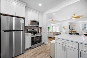 Una cocina moderna con electrodomésticos de acero inoxidable, armarios blancos y una isla central.