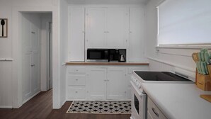A compact kitchen with white cabinetry, a microwave, a coffee maker, and a stove. - Pet-friendly 1917 Art Deco 2BR in Olympia, walkable downtown with workspace, parking, and modern comfort (Olympia)