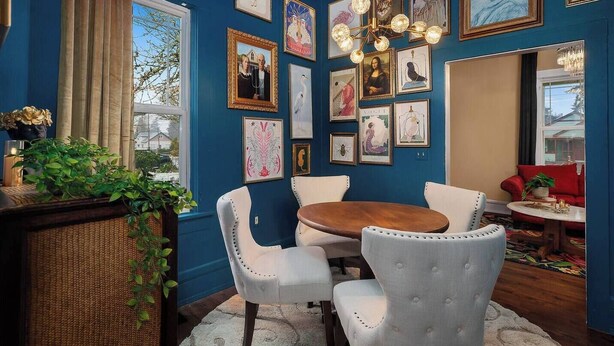 A dining area with a round wooden table, white upholstered chairs, and a chandelier. - Pet-friendly 1917 Art Deco 2BR in Olympia, walkable downtown with workspace, parking, and modern comfort (Olympia)