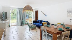Een lichte, open woonruimte met een eettafel, stoelen, een bank en een groot raam.