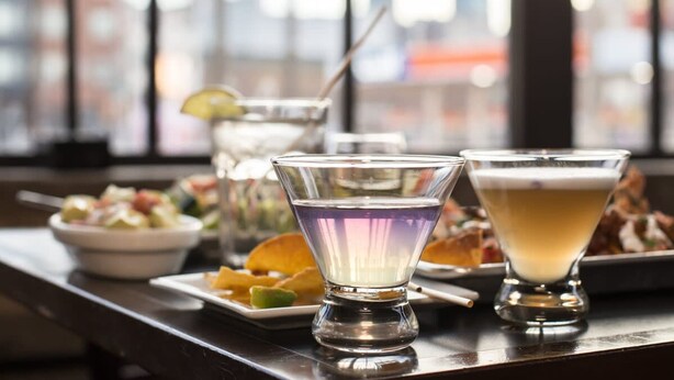 A bar setting with various drinks and dishes, including a martini glass, a cocktail glass, and a bowl of food. - Sosuite Studio Penthouse w W/d, Gym, On-site Bar (Philadelphia)
