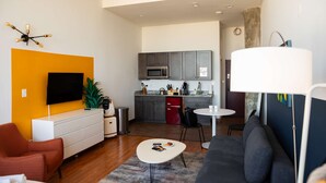 Een moderne woonkamer met een bank, een televisie en een eethoek met een tafel en stoelen.