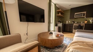 A modern living room with a flat-screen TV, a round wooden coffee table, and a sofa. - Sosuite NEW 2BR Apt w W D Split Level (Philadelphia)