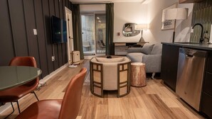 Ein modernes Wohnzimmer mit Essbereich, einer Couch, einem Couchtisch und einer Küchenzeile inklusive Geschirrspüler.