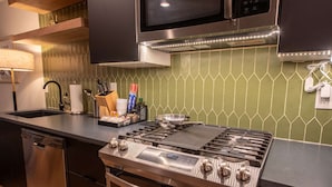 Cozinha moderna com fogão de aço inoxidável, micro-ondas e lava-louças.