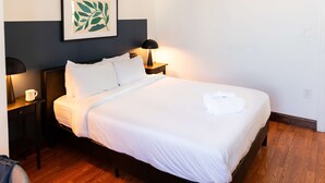 A neatly made bed with white linens, two bedside lamps, a framed artwork on the wall, and wooden flooring. - Sosuite 2BR Apt w W/d, Gym, On-site Restaurant (Philadelphia)