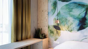 Una habitación con estante de madera, planta en maceta y pared con diseño abstracto en color verde.