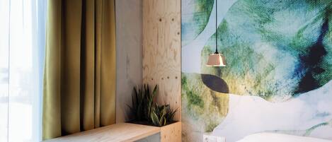 Una habitación con estante de madera, planta en maceta y pared con diseño abstracto en color verde.