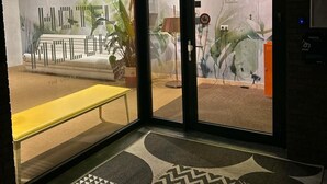 Un hall de hotel de diseño moderno, con un banco, una planta y un gran escaparate con el letrero 'HOTEL'.