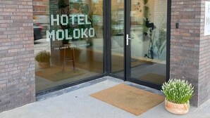 La entrada del Hotel Moloko, con puertas de vidrio y fachada de ladrillo.