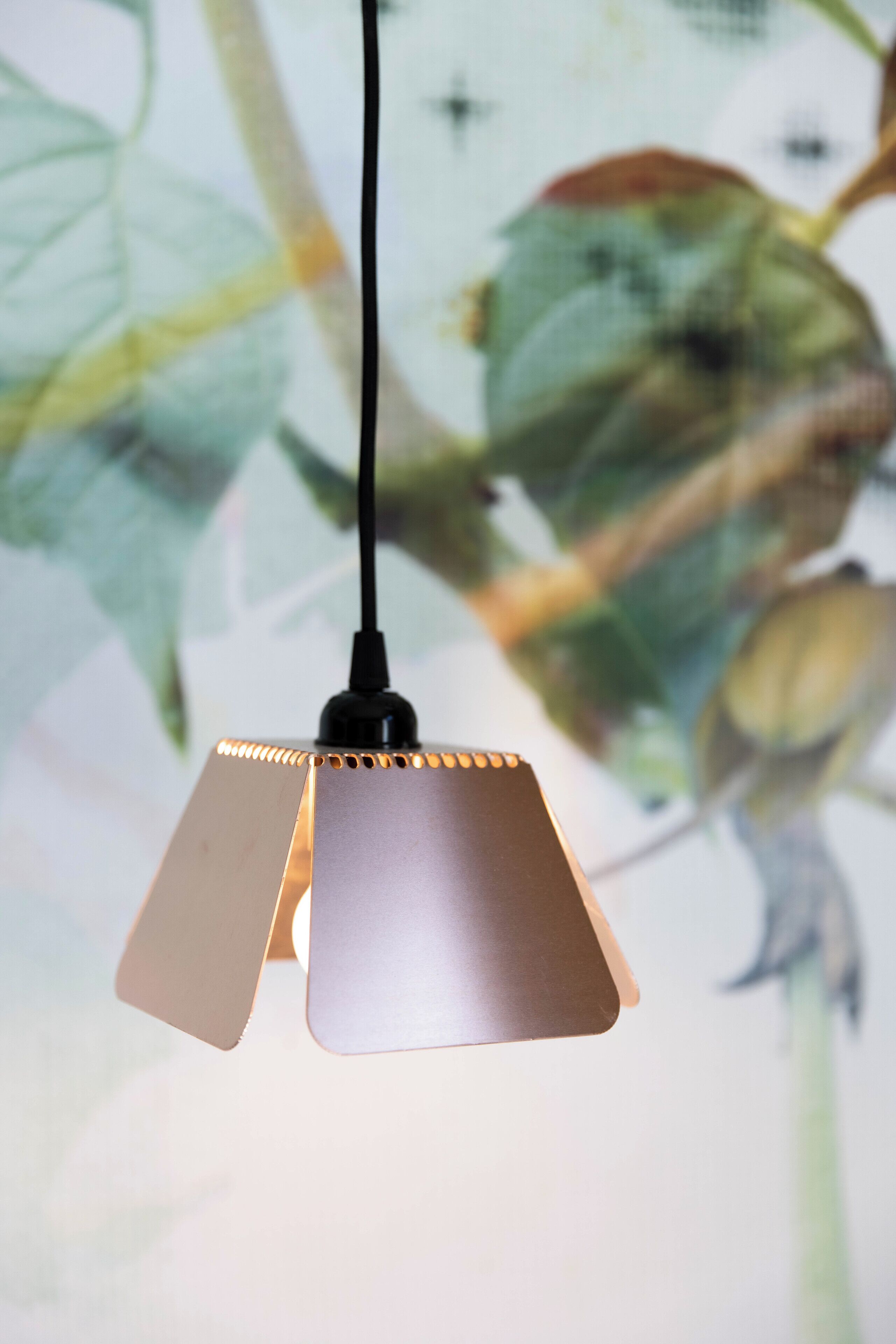 A pendant light with a black cord and a metallic finish.