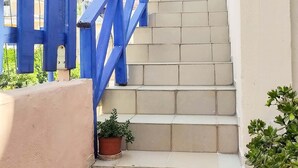 Un escalier de couleur beige, avec des rampes bleues, mène à un escalier en colimaçon.