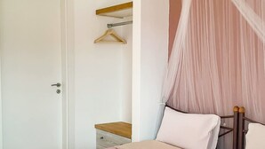 A bedroom with a bed, a bedside table, a hanging light fixture, and a door. - Dinas Apartment - Alonnisos Summer Haven (Alonissos)